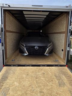 Car loaded inside enclosed trailer with rear ramp open